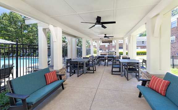 A patio with a table and chairs and a ceiling fan.