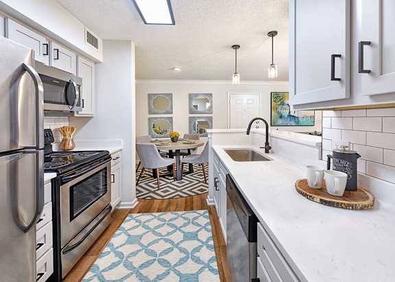 A kitchen with a refrigerator, microwave, and sink.