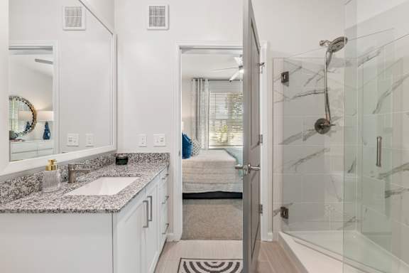A bathroom with a marble countertop and a walk-in shower.