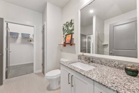 A bathroom with a toilet, sink, and mirror.