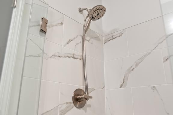A shower head mounted on a wall with marble tiles.