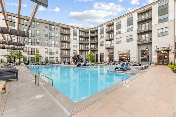 A large swimming pool is surrounded by apartment buildings.