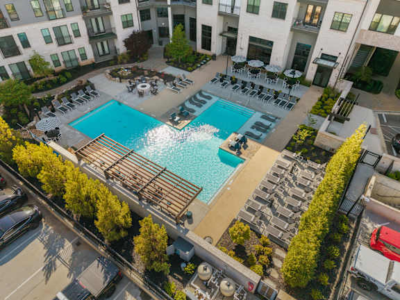 A large swimming pool surrounded by lounge chairs and trees.