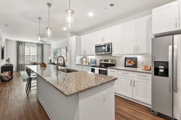 A modern kitchen with a granite countertop and stainless steel appliances.