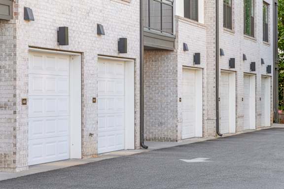 A row of white garage doors on a brick building.
