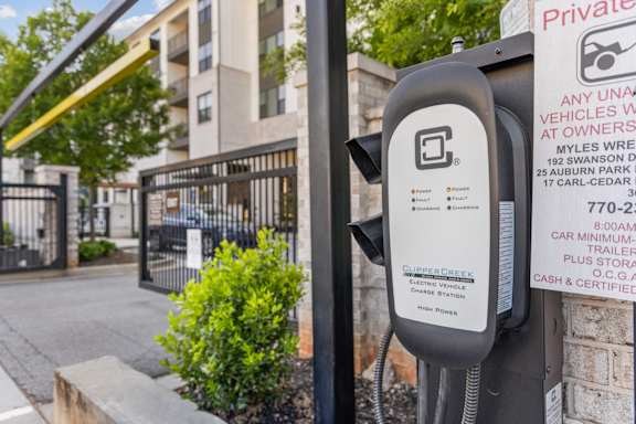 A parking meter in front of a gated entrance to an apartment complex.