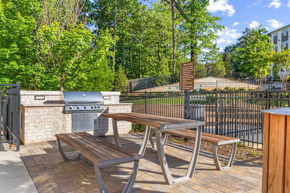 A wooden bench with metal legs sits on a brick patio.