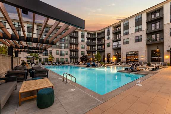A large swimming pool is surrounded by lounge chairs and umbrellas.