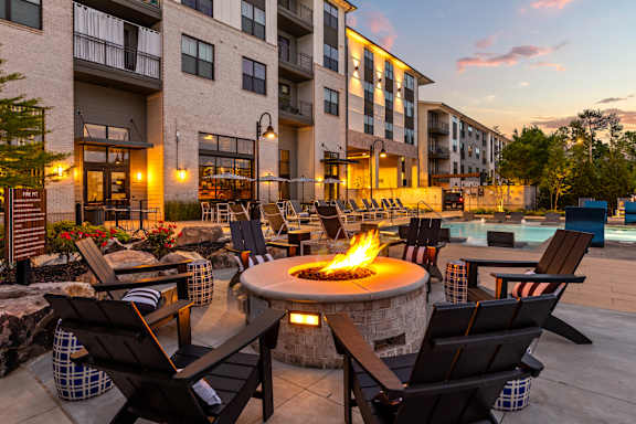 A fire pit sits in the middle of a patio surrounded by chairs.