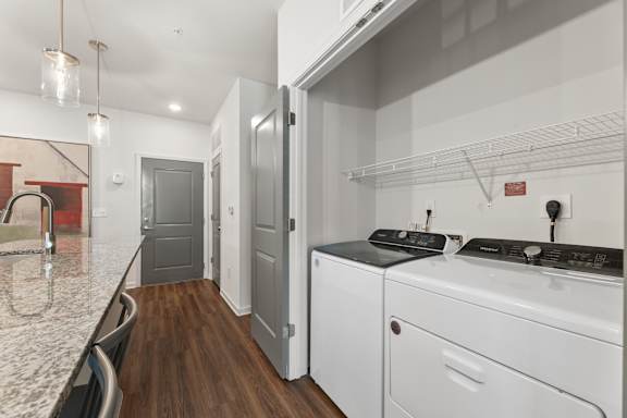 A modern kitchen with white appliances and a marble countertop.