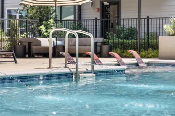 A pool with a ladder and a sun umbrella.