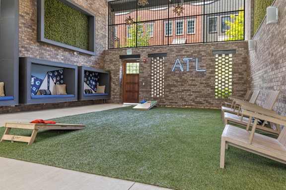 A backyard with a lawn, a bench, and a cornhole game set up.