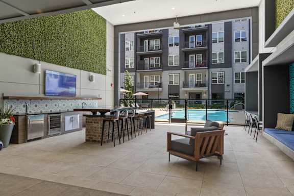 A modern outdoor kitchen area with a bar and chairs.