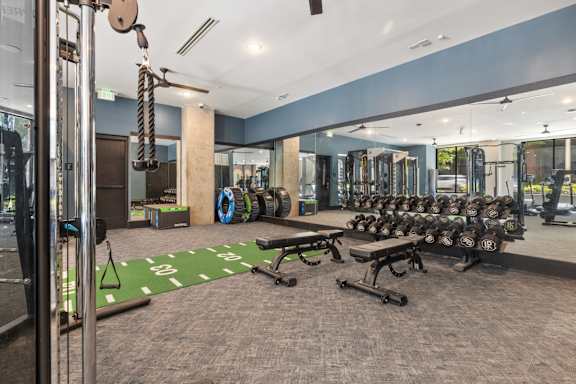 A gym with a variety of equipment including weights and a bench.