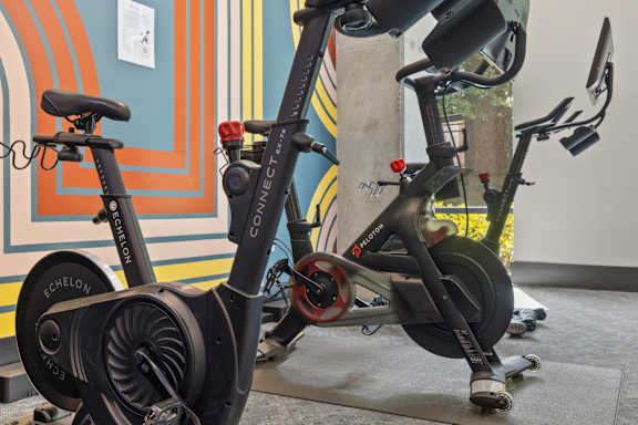 A stationary exercise bike is leaning against a wall.