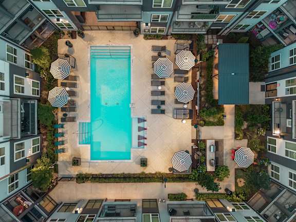 An aerial view of a pool surrounded by lounge chairs and umbrellas.