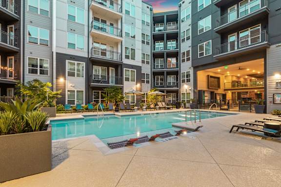 A large swimming pool in front of apartment buildings.