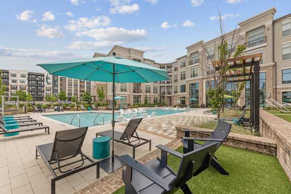 A sunny day at the poolside with chairs and umbrellas.