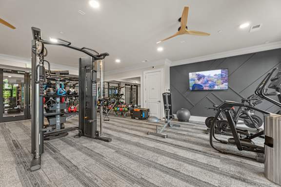 A spacious home gym with a variety of equipment including a treadmill, weights, and a television.