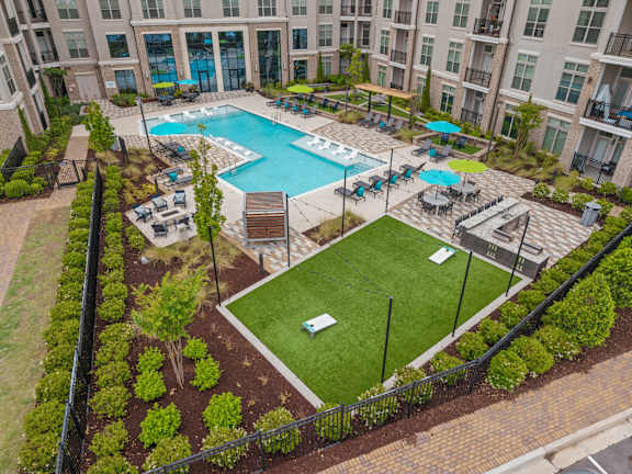 A large outdoor pool surrounded by a grassy area and a fence.