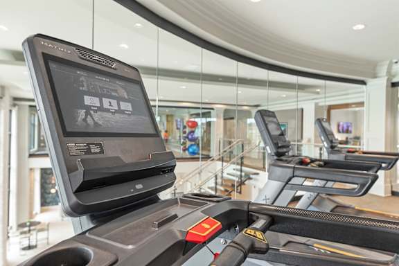 A treadmill with a screen on top is in a well-lit room.
