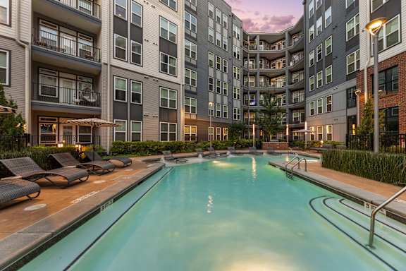 A large indoor pool surrounded by lounge chairs and apartment buildings.