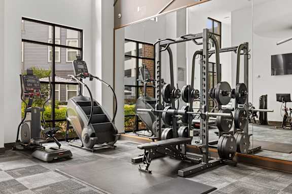 A gym with a variety of equipment including treadmills, weights, and exercise machines.