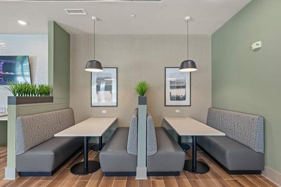 A modern dining area with grey booths and white tables.