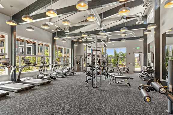 A gym with a variety of equipment including treadmills, weights, and exercise machines.