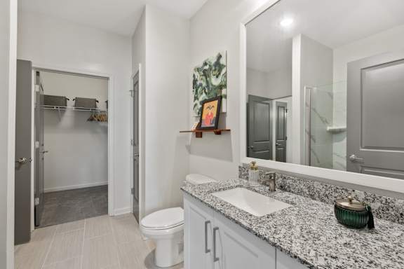 A bathroom with a toilet, sink, and mirror.
