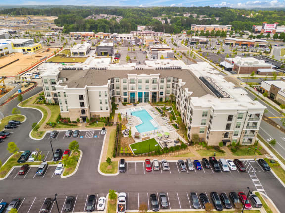 an aerial view of a large apartment complex with a pool in the middle of the parking lot