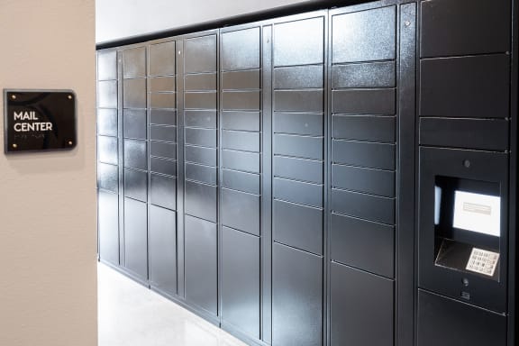 the mail center has a wall of metal lockers with a mailbox