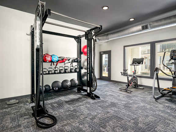 A gym with a variety of equipment including a squat rack, kettlebells, and a treadmill.