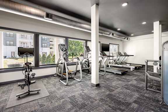 A gym with a variety of equipment including treadmills, stationary bikes, and weight machines.