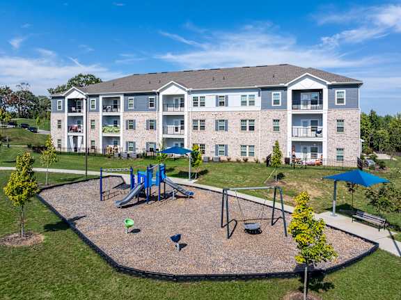 A playground area is located in front of a large apartment building.