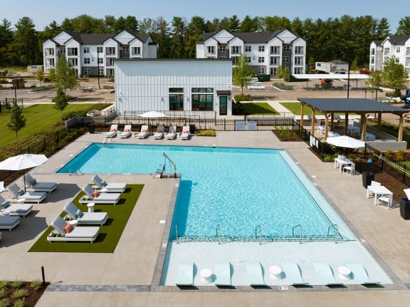 an aerial view of a swimming pool with lounge chairs around it