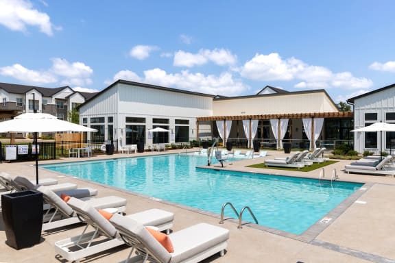 a swimming pool with lounge chairs in front of a building