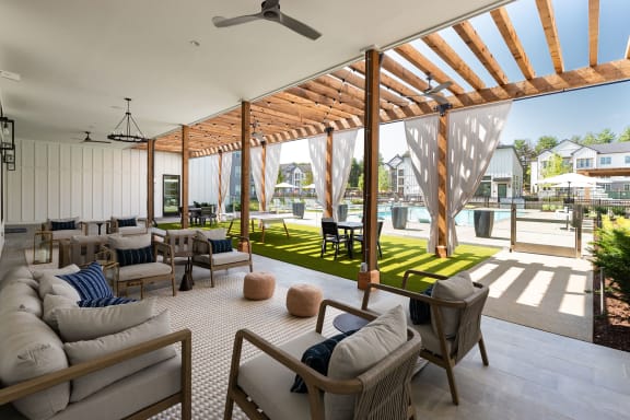 a living room with couches and chairs under a wooden roof
