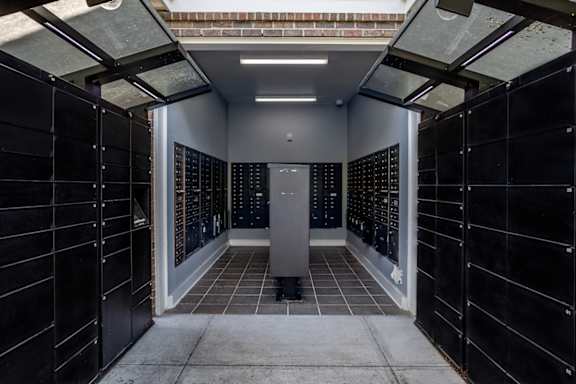 A long hallway with black lockers on both sides and a white door in the middle.