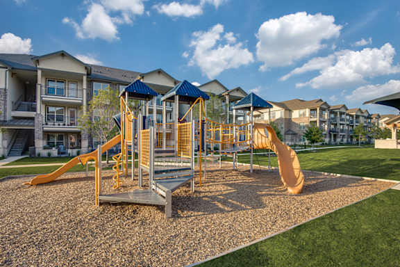 A playground with a yellow slide and a blue canopy.