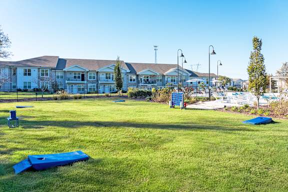 A grassy field with a blue tarp and a white building in the background.