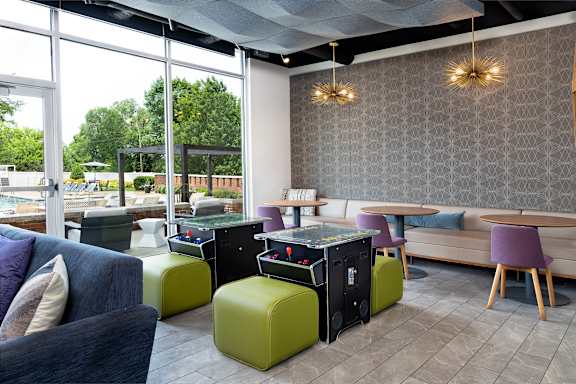 A modern living room with a purple couch, green ottoman, and a black coffee table.