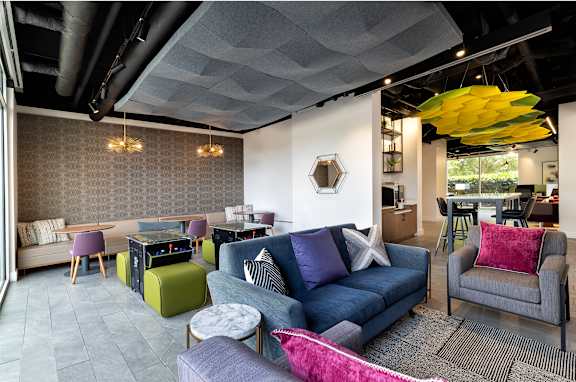 A living room with a grey couch and a yellow hanging light fixture.
