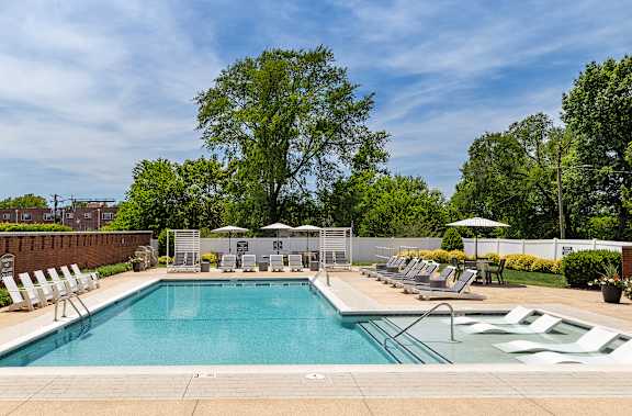 A large swimming pool surrounded by trees and lounge chairs.