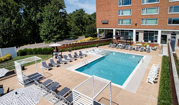 A large swimming pool surrounded by lounge chairs and umbrellas.