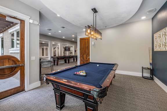 A pool table in a room with a light hanging above it.