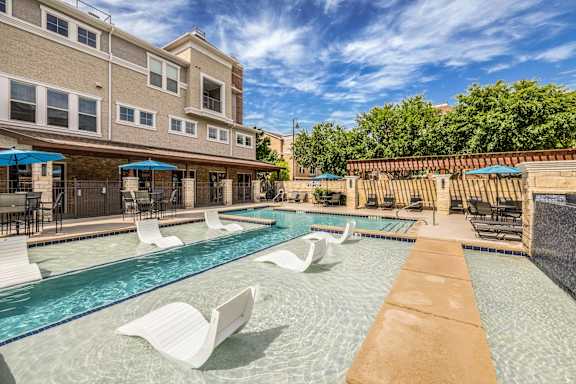 A pool with white chairs and a building in the background.