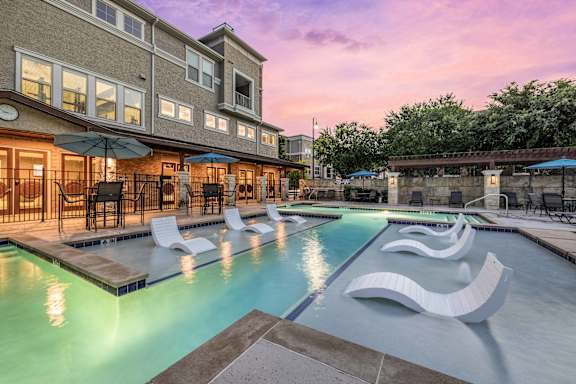 A large outdoor pool area with lounge chairs and umbrellas.
