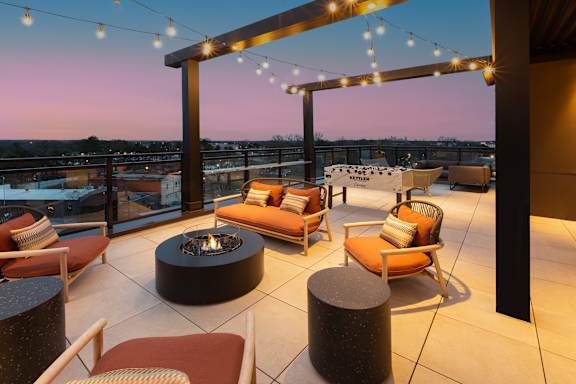 a rooftop terrace with chairs and a fire pit