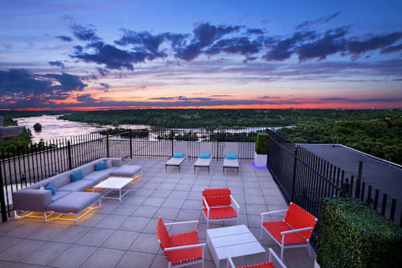 a rooftop terrace with a view of the ocean and a sunset